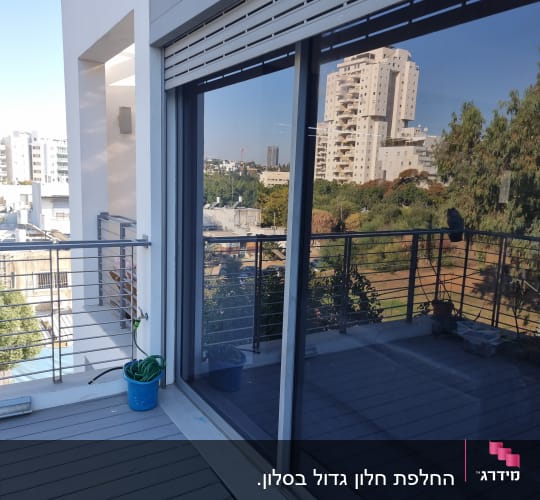 חלון זכוכית גדול עם השתקפות של בניינים ועצים.